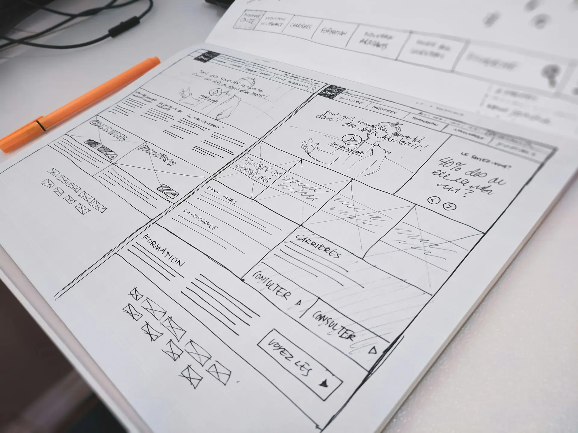 Hand-drawn layout sketch on paper beside a pen on a desk
