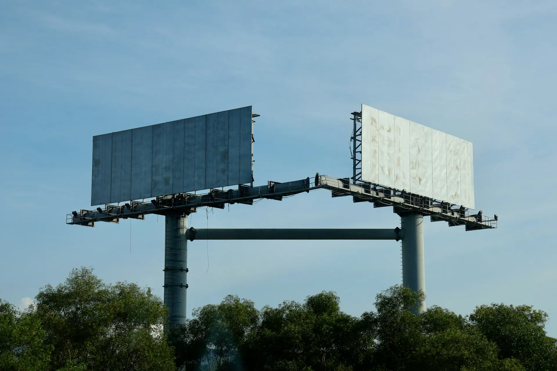 Two empty advertising billboards against a clear blue sky