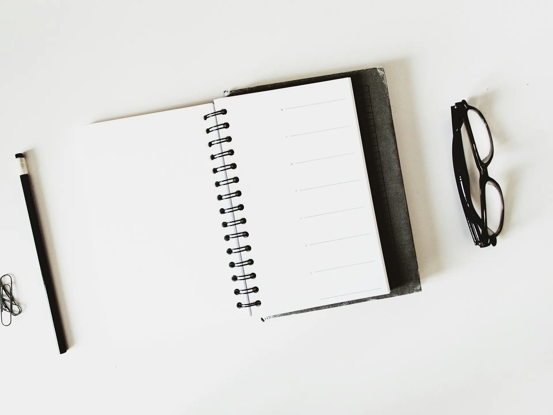 Spiral notebook and a black pen on a plain pale background