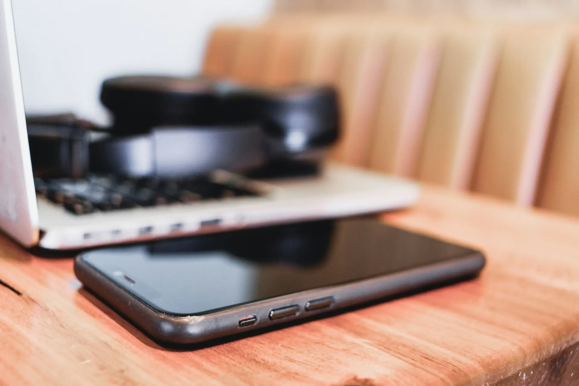 Camera and phone resting on a warm wooden desk in a creative workspace